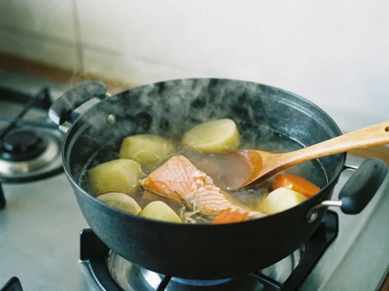 A pot of soup with salmon and vegetables